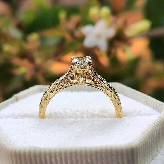 Vintageinspirerad diamantring i guld med detaljerat mönster i en smyckesask.