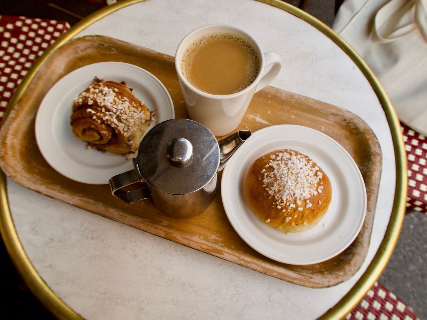 Kaffekopp, kanna och två bullar på ett serveringsfat